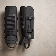 Black snake gaiters flat lay showing the reinforcement panels and dual buckles